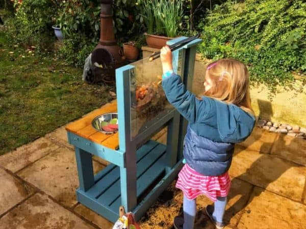 Girl playing outside with worm mud kitchen
